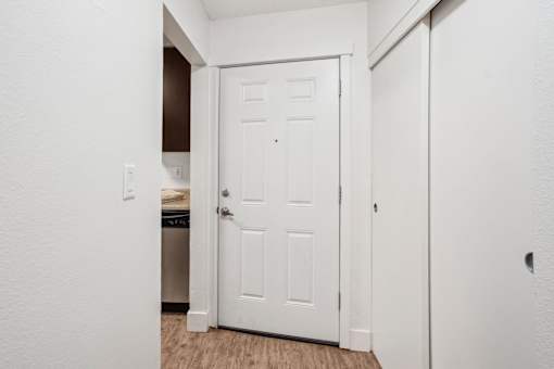 A white door is in a hallway with a light switch on the wall.