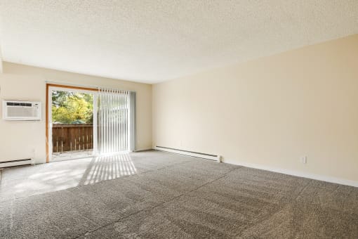 an empty living room with a sliding glass door to a patio