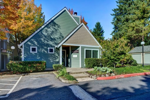 the front of a green house with trees and a sidewalk