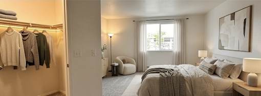 A bedroom with a large bed, a chair, a window with curtains, and a painting on the wall.