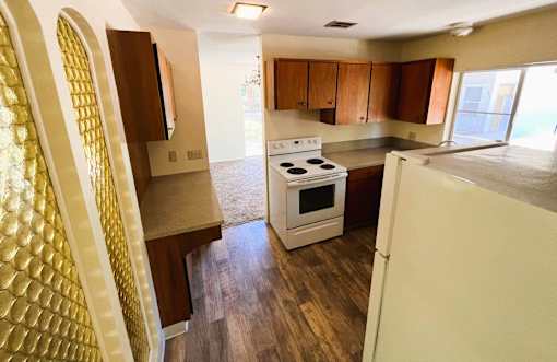 A kitchen with a white stove and wooden floors.