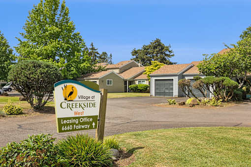 A sign for the Village at Creekside leasing office is in front of a building.