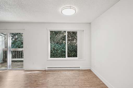 A room with a window and a door leading to a balcony.