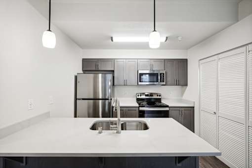 A modern kitchen with a stainless steel refrigerator, microwave, and oven.