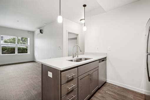 A kitchen with a sink, cabinets, and a window.