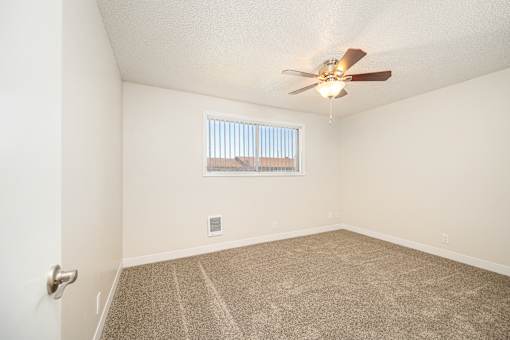 A room with a ceiling fan and carpeted floor.