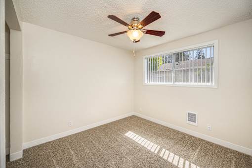 A room with a ceiling fan and a window with blinds.