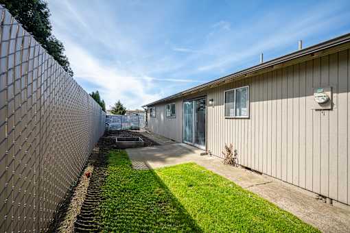 A sunny day at a residential complex with a fence and grassy area.