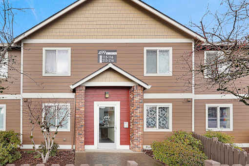 A brown house with a red door and a sign on the front.