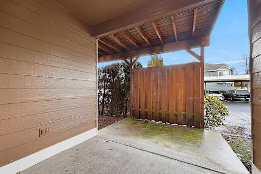 A wooden fence and a small tree are visible from a covered outdoor area.