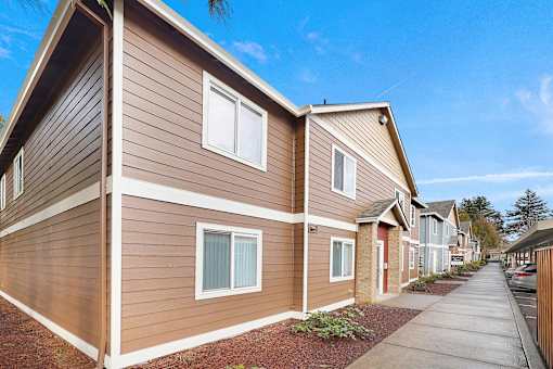 A row of houses with brown siding and red doors.