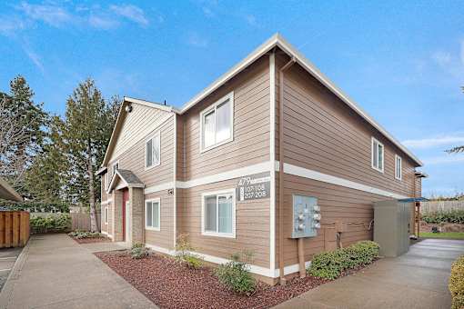 A brown house with a garage door and a mailbox on the front.