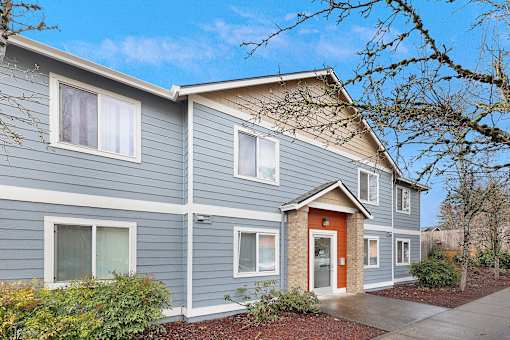 A grey house with a red door and windows.