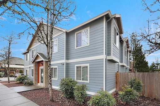 A grey house with a red door and windows.