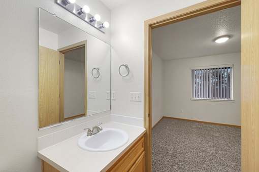 A bathroom with a sink, mirror, and lighting fixture.
