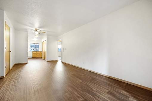 A long empty room with wooden floors and white walls.