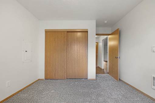 A room with a carpeted floor and a wooden door.