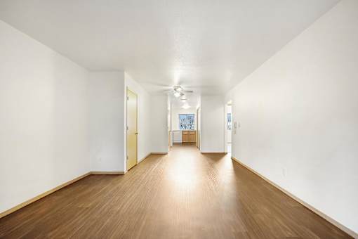 A long hallway with wood floors and white walls.