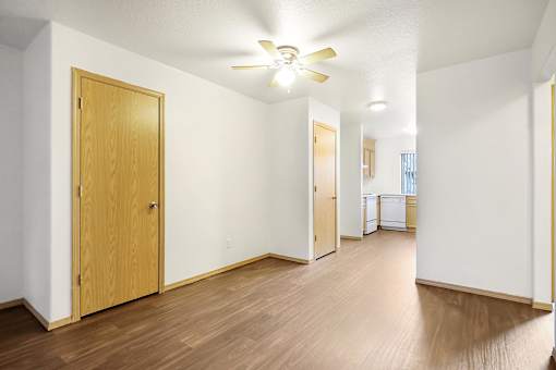 A room with a ceiling fan and wooden floors.