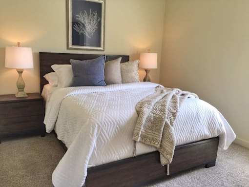 A bed with a white comforter and a brown blanket is in the center of the image.