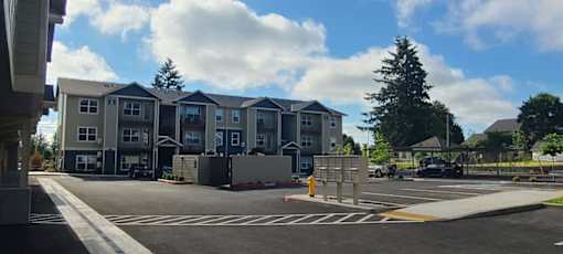A parking lot in front of a large apartment complex.
