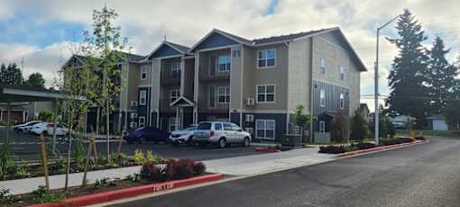 Apartment complex with a parking lot in front.