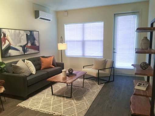 A living room with a grey couch, a coffee table, and a painting on the wall.