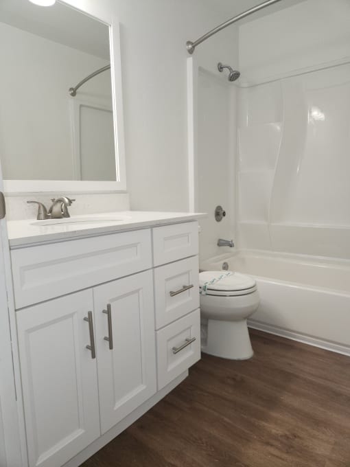 a bathroom with white cabinets and a white bathtub