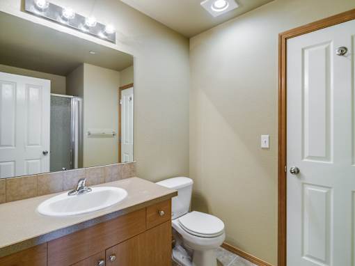 A bathroom with a toilet, sink, and mirror.