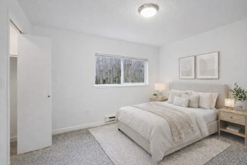 A bedroom with a large bed and a window with a view of trees outside.
