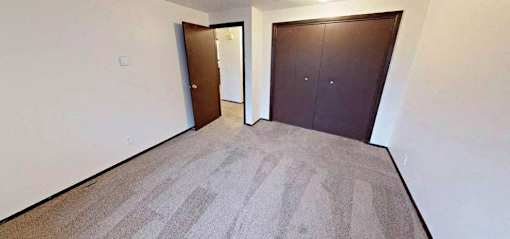 A room with a carpeted floor and two brown doors.