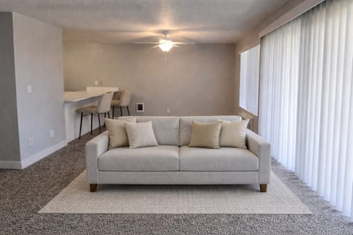 A living room with a couch, a rug, and a table with chairs.