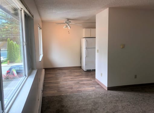 A room with a window, a ceiling fan, and a refrigerator.
