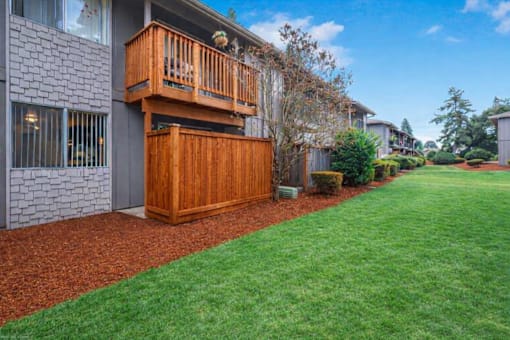 A house with a wooden deck and a red mulch garden bed.