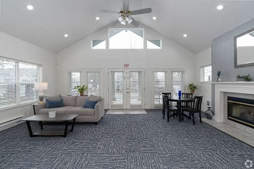 A living room with a grey carpet and a fireplace.