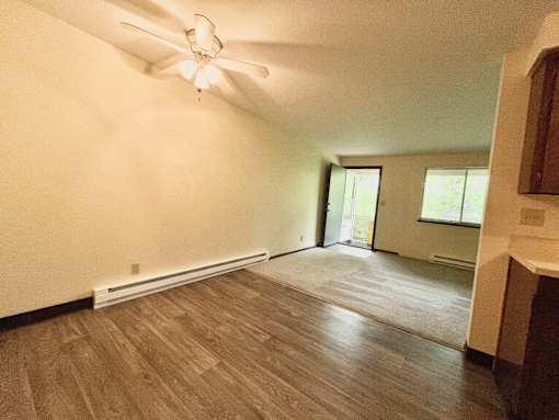 A room with a ceiling fan and wood flooring.