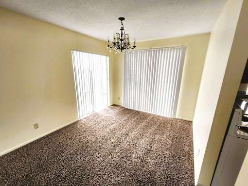 A room with a chandelier and a carpeted floor.