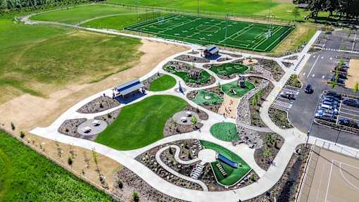 A park with a green lawn, a basketball court, a tennis court, a soccer field, and a playground.