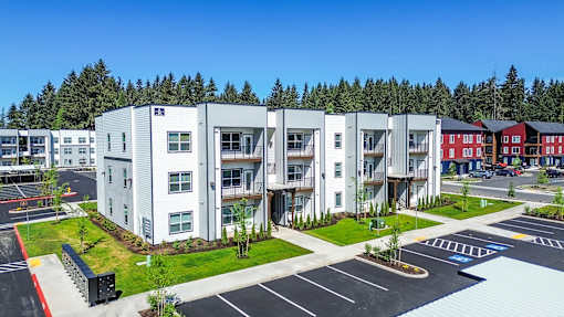 A modern apartment complex with a parking lot in front.