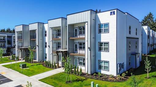 A row of modern townhouses with balconies and green lawns.