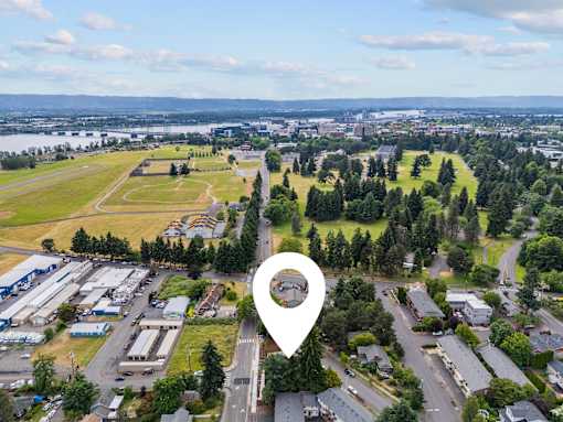 A bird's eye view of a town with a large green field and a river in the distance.
