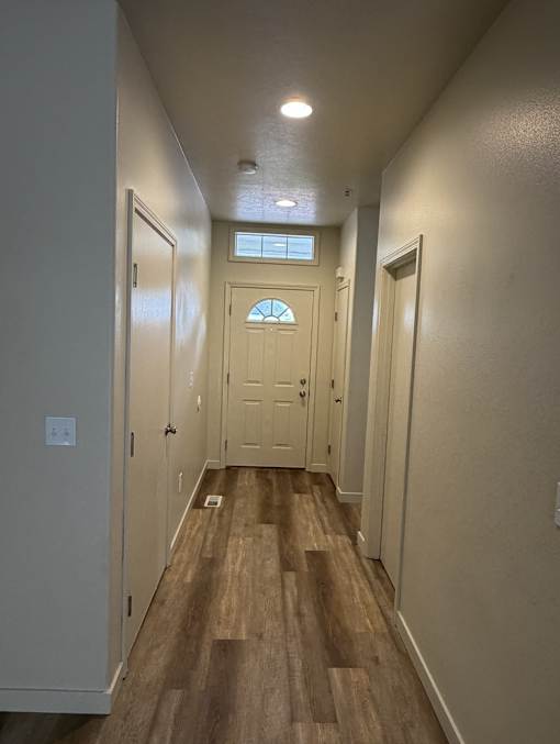 A hallway with a wooden floor and white walls.
