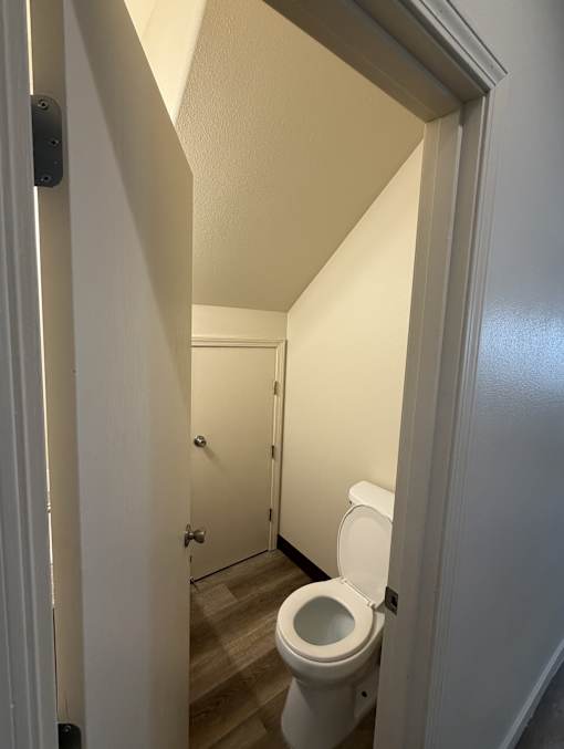 A white toilet in a narrow hallway.