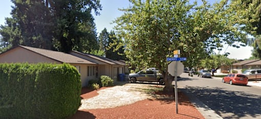 A blue car is parked in front of a white building.
