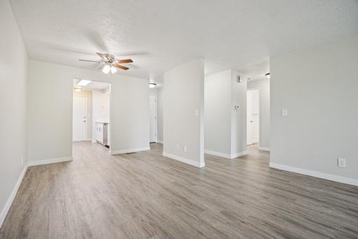 A room with a ceiling fan and wood flooring.