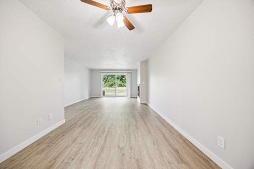 A room with a ceiling fan and wooden flooring.