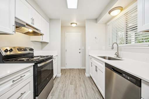 A modern kitchen with white cabinets and stainless steel appliances.