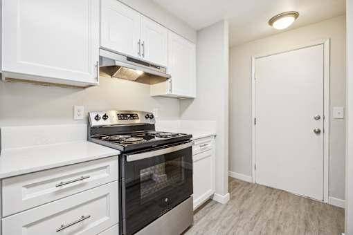 A kitchen with white cabinets and a black stove top oven.