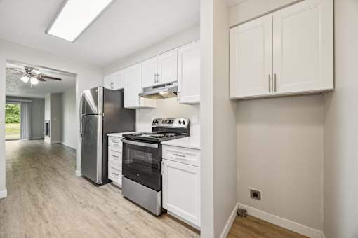 A kitchen with white cabinets and a stainless steel refrigerator.