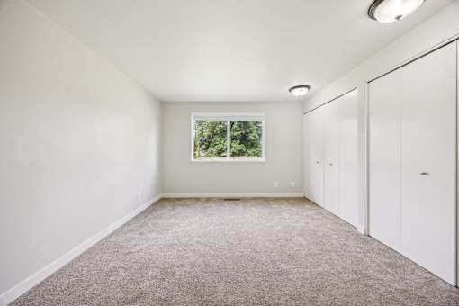 A room with a window and a carpeted floor.